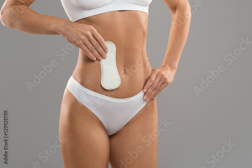Female Hygiene. Young unrecognizable lady in white underwear holding clean menstrual pad
