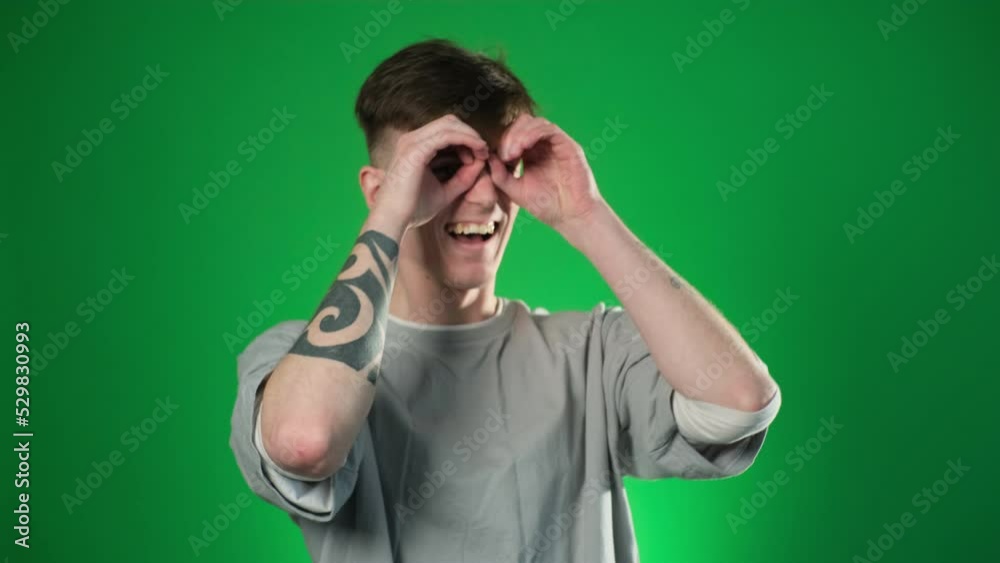 Man looking through fingers on eyes, doing binoculars Man looking through fingers on eyes, doing binoculars