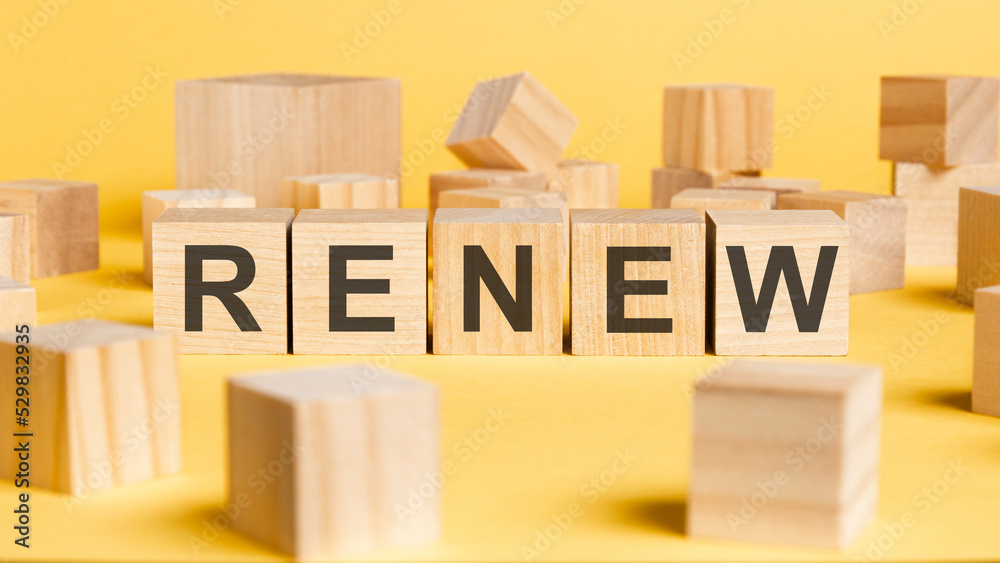 Samolepka the word renew written on wooden cubes on yellow background