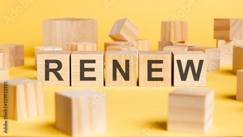 the word renew written on wooden cubes on yellow background photo
