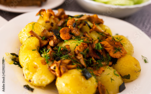 baked potatoes with chanterelles, served with herbs on white plate