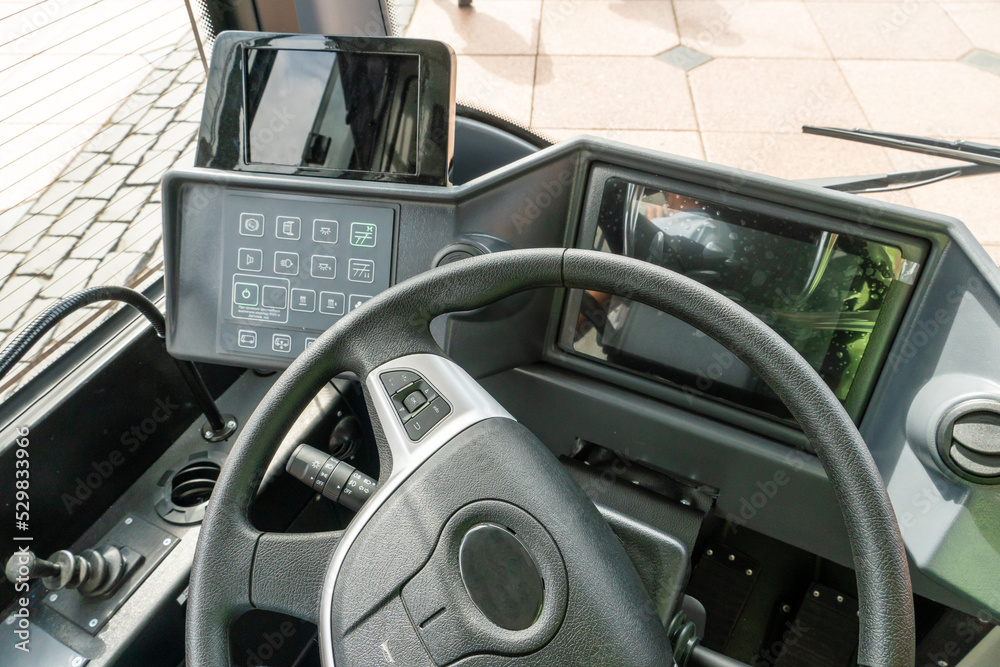 View of the steering wheel and dashboard of a new modern bus. Urban public transport. There are many different buttons and electronic devices in the cab of the car.