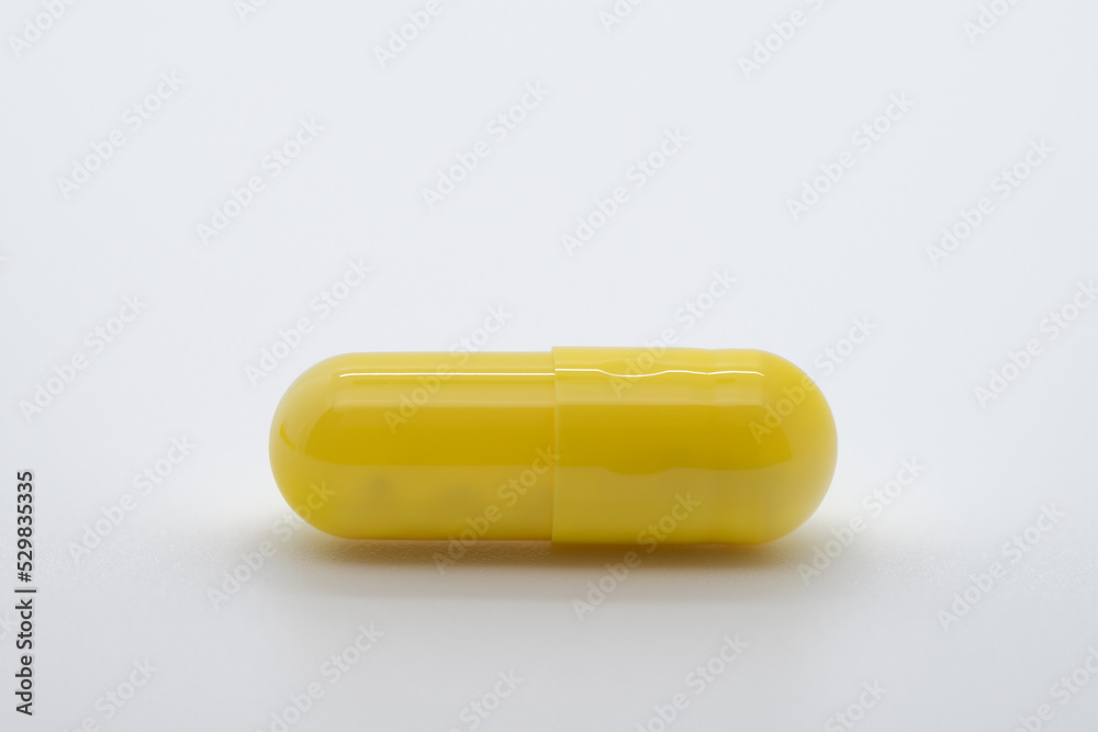 Pill in yellow color on white background, medicine, cropped image