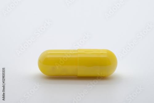Pill in yellow color on white background, medicine, cropped image