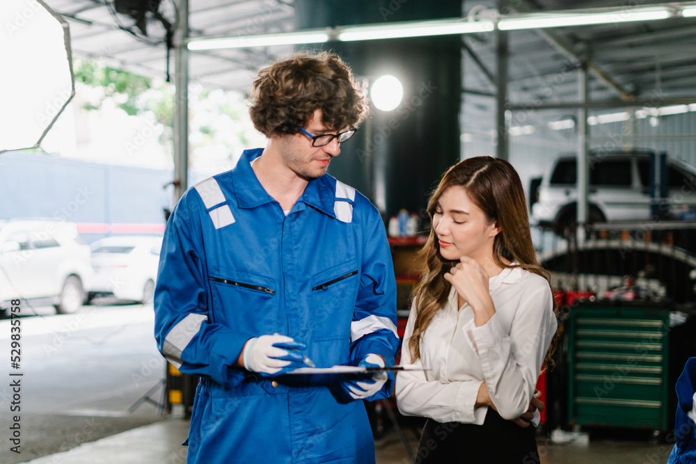 Naklejka premium Professional service, Auto car repair service center Concept, Mechanic holding a clipboard and showing the car checking list and repaired item to woman customer in the garage