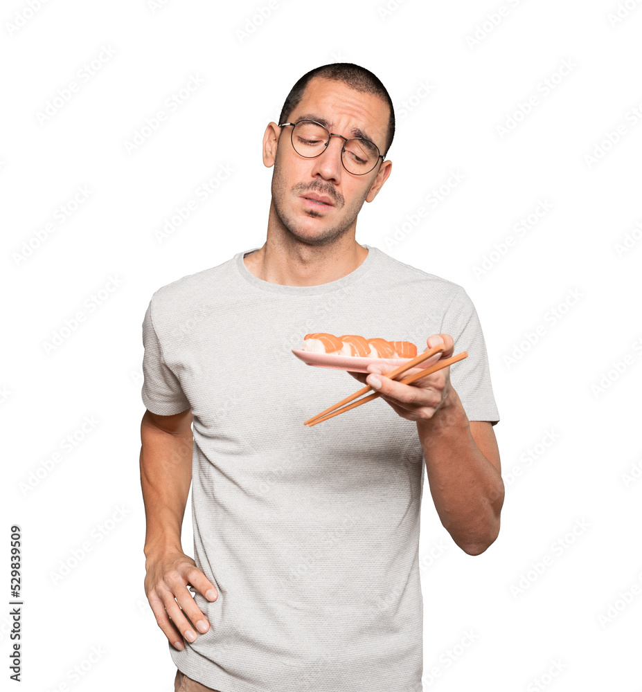 Young man using chopsticks to eat sushi Young man using chopsticks to eat sushi