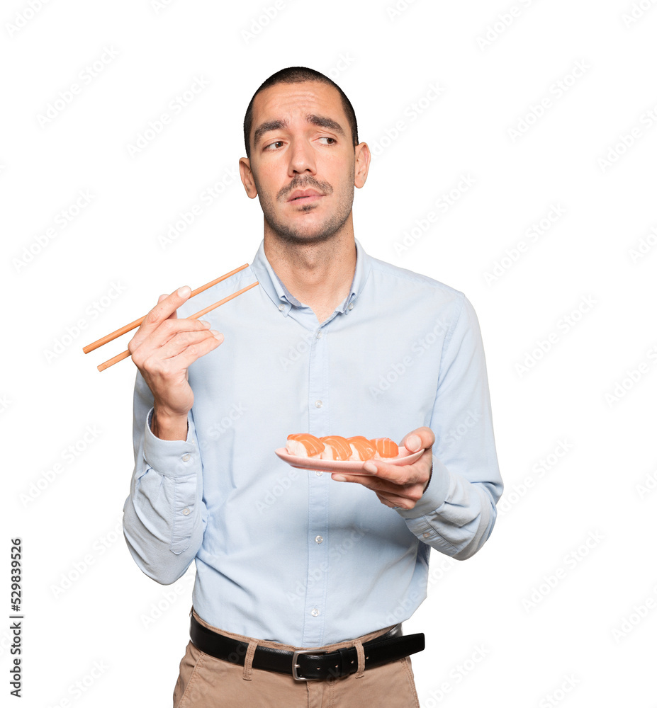 Young man using chopsticks to eat sushi