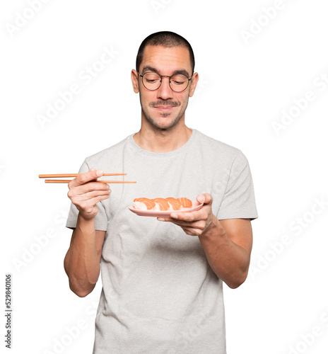 Young man using chopsticks to eat sushi