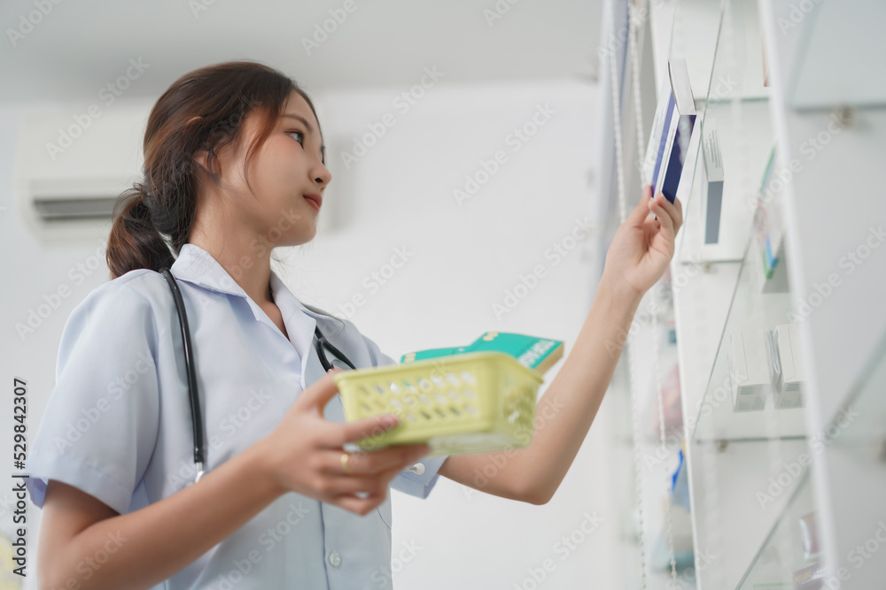 Medicine and health concept, Female pharmacist is taking medicine boxes from shelves into basket Medicine and health concept, Female pharmacist is taking medicine boxes from shelves into basket