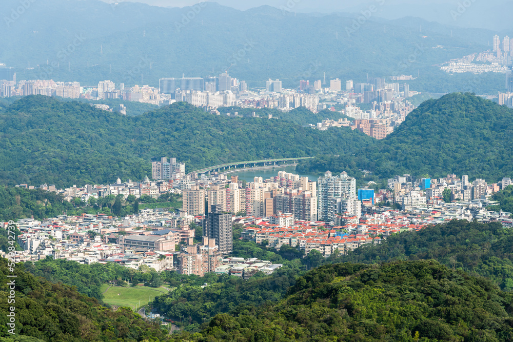 Overlooking the urban panoramic view of the Neihu and Nangang in Taipei, Taiwan, surrounded by green forests and mountains.