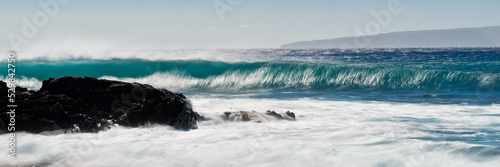 A large, long blue wave crashes on the shores of Maui Hawaii near La Perouse Bay. photo