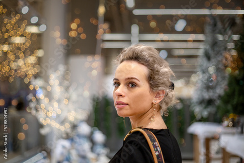 a woman looks surprised and delighted with the best hopes for the future in the New Year and Christmas decorations in the store