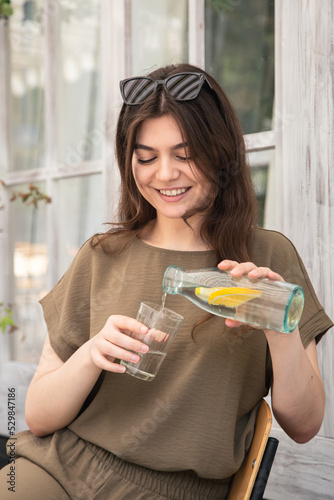 Attractive young woman drinks water with lemon.