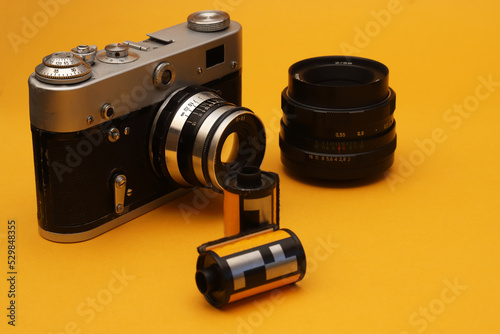Old film camera with accessories on an orange background. Shallow depth of field
