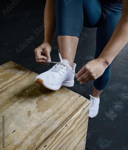 Woman lacing up running shoes at the gym