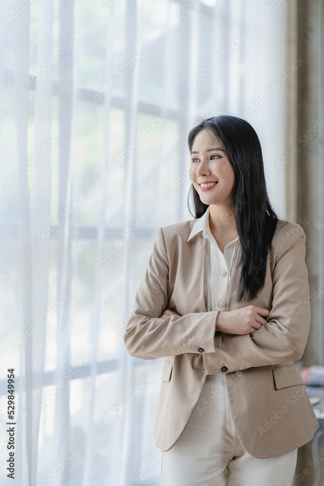 Successful young Asian businesswoman smirking at her desk in the office vertical picture Successful young Asian businesswoman smirking at her desk in the office vertical picture