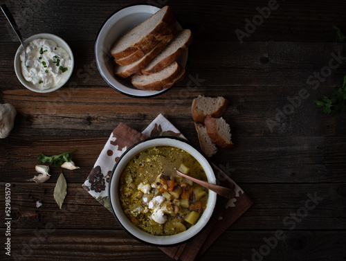 Vegetarian soup and bread in a rustic setting, enameled bowl. wooden table