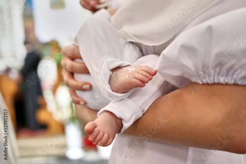 The legs of a newborn during baptism in the church. Baptism and anointing ceremony.