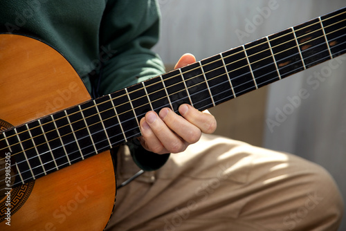 Plays the guitar. Guitar strings and fingers. Musical instrument. Man and guitar.