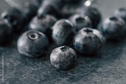Macro photography, blueberries scattered on a dark surface.