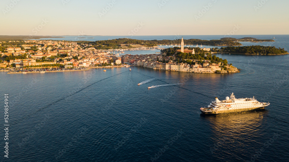 Fototapeta premium Beautiful Rovinj town (popular tourist resort and an active fishing port) at sunset. Aerial photo. The old town of Rovinj, Istria, Croatia.