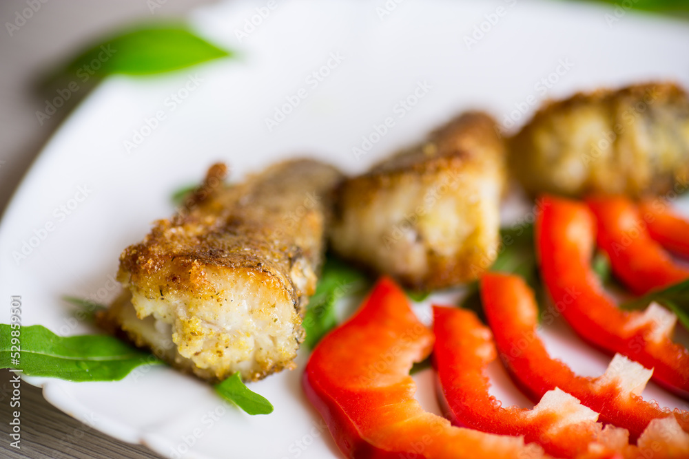 Pieces of fried hake fish in a plate with pepper Pieces of fried hake fish in a plate with pepper