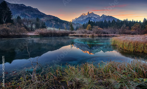 Amazing Zelenci lake  natural Scenery during Sunrise. Awesome sunny Landscape at Julian Alps under sunlight. Beautiful sunrise with Lake and majestic Mountains. Wonderful picturesque Scene. Slovenia