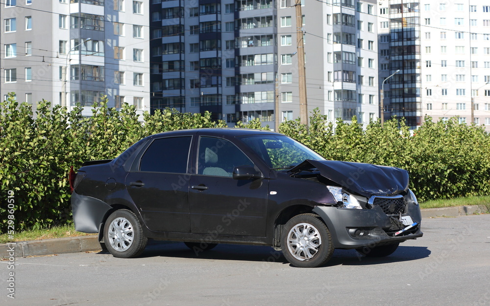 A black wrecked car after an accident is parked on the street, Kollontai Street, St. Petersburg, Russia, September 2022