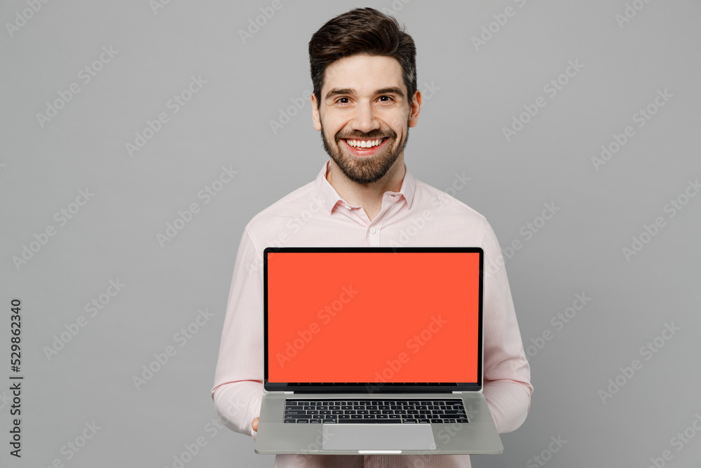 Young caucasian IT man 20s he wearing basic white shirt hold use work on laptop pc computer with blank screen workspace area isolated on plain grey background studio portrait People lifestyle concept Young caucasian IT man 20s he wearing basic white shirt hold use work on laptop pc computer with blank screen workspace area isolated on plain grey background studio portrait People lifestyle concept