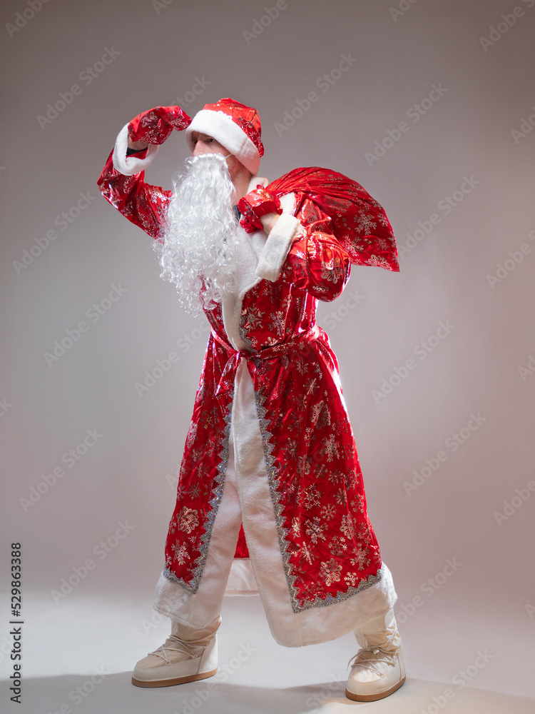 Santa Claus with a bag of gifts is in a hurry for the New year ,a holiday for children, New Year's gifts, in full growth on a gray background