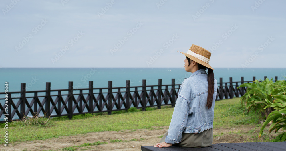 Travel woman sit on the bench and look at the sea