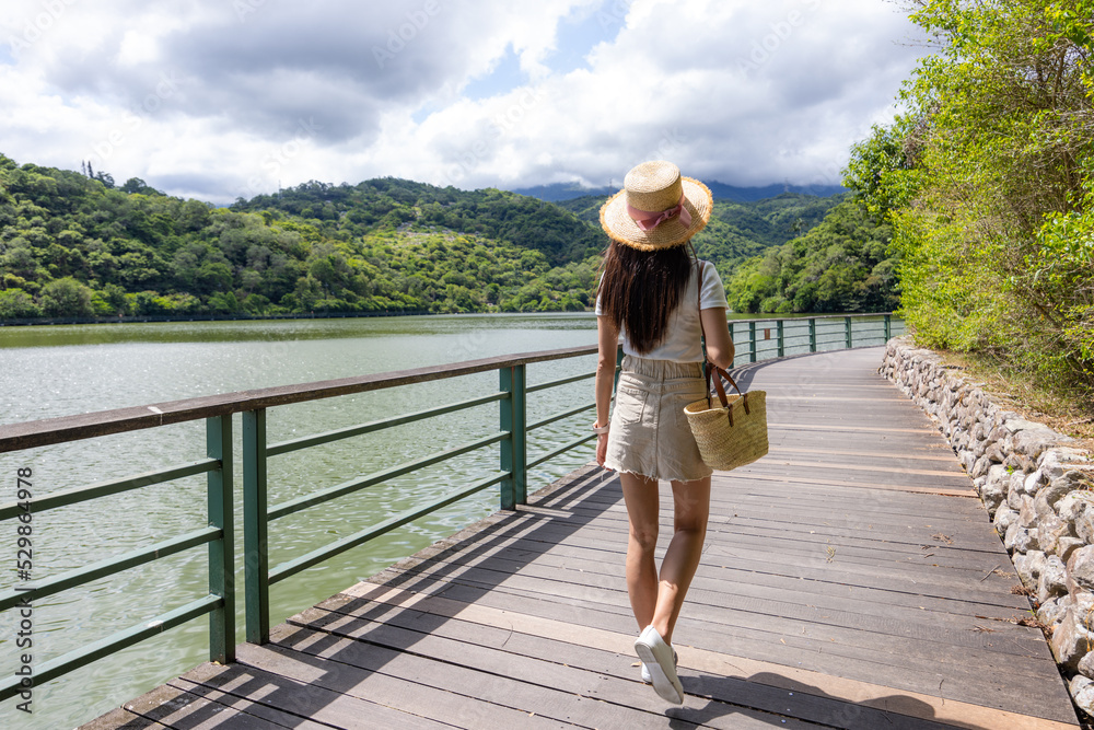 Asian woman walk on the lakeside wooden path