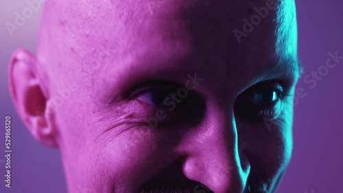 Curious joy. Flirting man. Neon light portrait. Happy conspiratorial guy looking winking on camera violet blue background closeup. photo