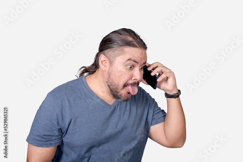 A man teases and ridicules someone over the phone. Sticking out his tongue out of habit. Communication concept. photo
