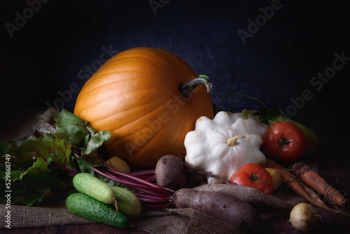Still life with vegetables on a dark background, pumpkin, tomatoes, healthy food.