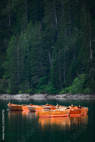 Obraz na płótnie Stunning view of some wooden boats floating on the Lake Braies (Lago di Braies) with a defocused green forest in the background. Lago di Braies is an alpine lake in the Dolomites, Italy w salonie