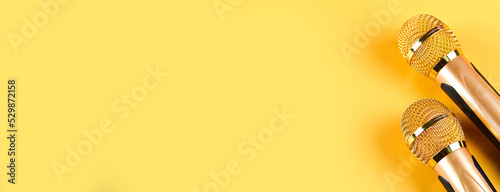 Two golden microphones isolated on yellow background close up