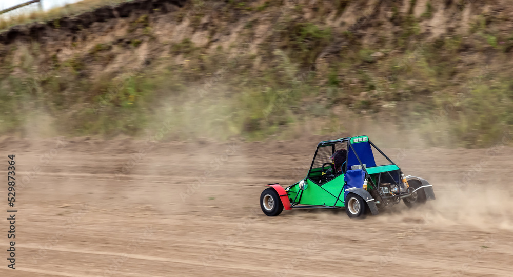 A small sports buggy with a child driving on a rally competition track during weekend training on a warm summer day.