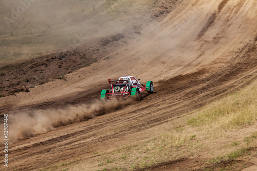 A sports buggy with a driver on a rally competition track during weekend training on a warm summer day. Fast driving with dirt from the wheels. © Aleksandr Kondratov