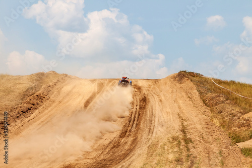 A sports buggy with a driver on a rally competition track during weekend training on a warm summer day. Fast driving with dirt from the wheels.