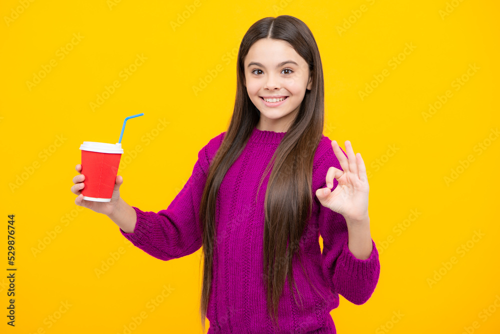 Child with coffee or tea cup isolated on yellow studio background. Teenage girl with take away beverage. Child with coffee or tea cup isolated on yellow studio background. Teenage girl with take away beverage.