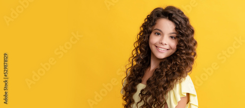cheerful child with long curly hair and perfect skin, healthy hair. Child face, horizontal poster, teenager girl isolated portrait, banner with copy space.