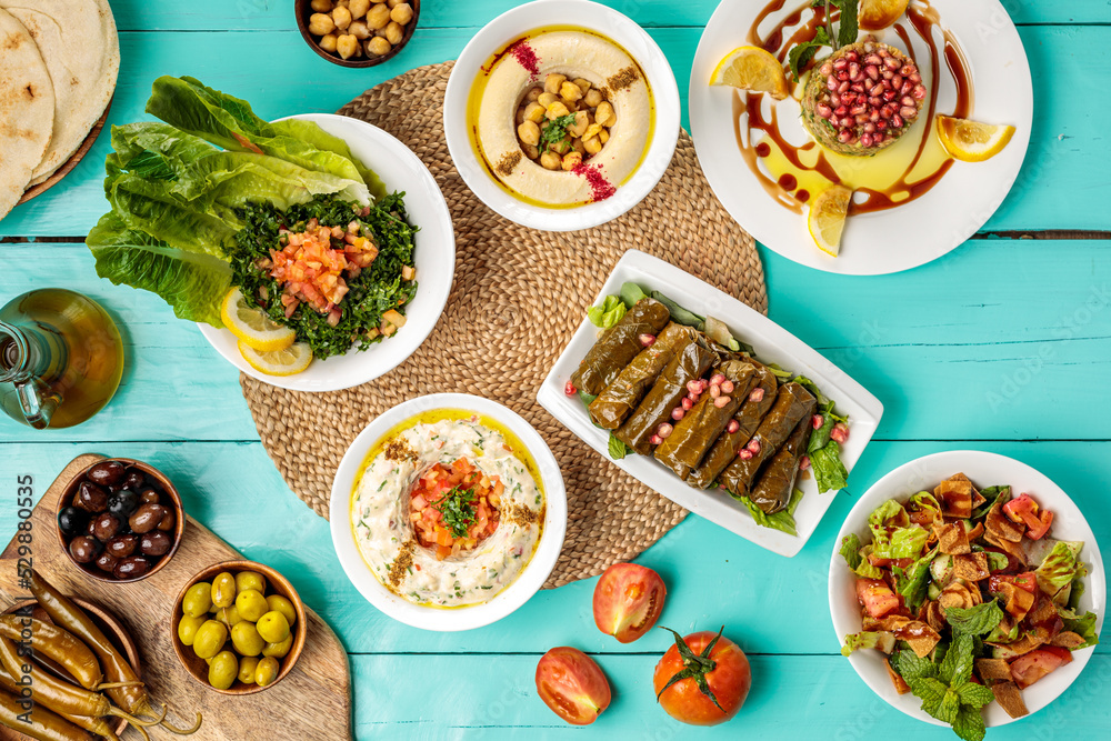 Assorted Arabian food Hommus Beiruti Meat, Baba Ghanouj , olive, chick peas, pita bread Vine Leaves, Tabbouleh, Fattoush, served in dish isolated on wooden table side view of middle eastern food