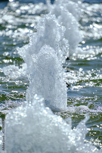 Foam jets of water and shine of sunlight from the fountain bright sunny day.