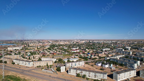 The small town of Balkhash is a view from a drone. A city in the middle of the steppe on the shore of Lake Balkhash. The metallurgical plant is smoking. Bad ecology. Low monotonous houses. Cars drive