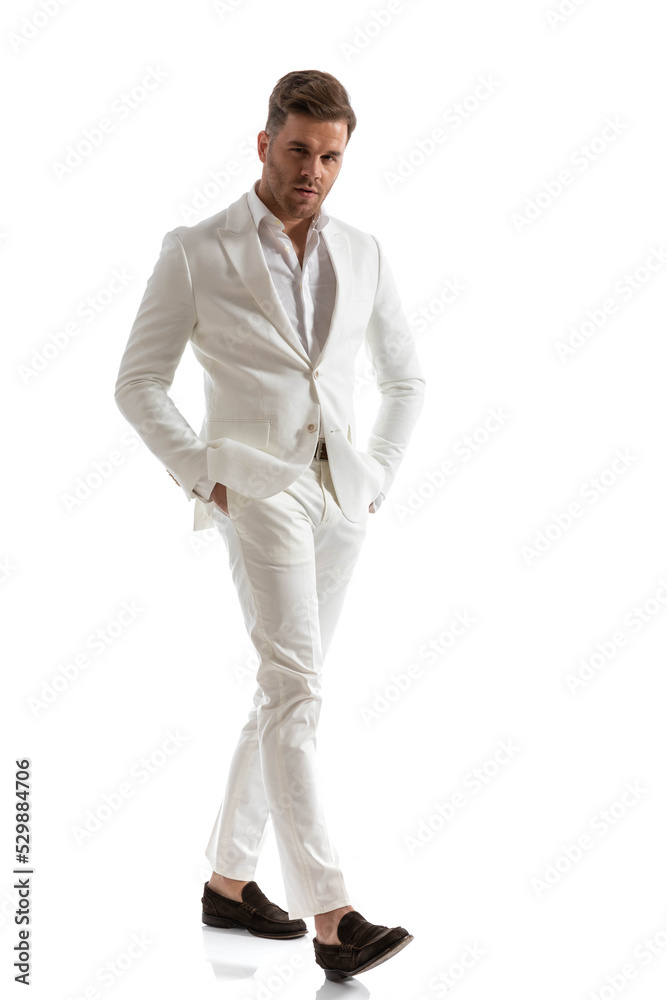 handsome man in white suit holding hands in pockets and walking handsome man in white suit holding hands in pockets and walking