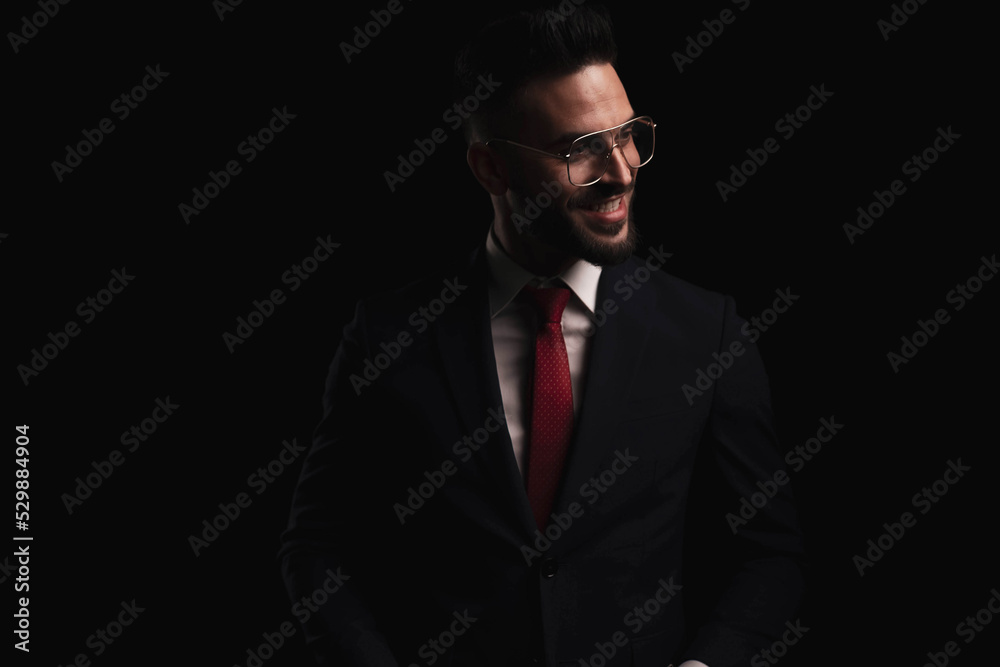 happy elegant man in black suit with red tie and glasses looking to side