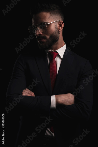 confident elegant businessman in suit crossing arms and looking to side