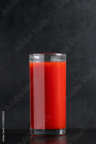 Delicious tomato juice on black background. Vegetable drink for vegan and healthy eating.