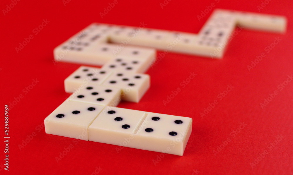 White domino laid out in the shape of a heart on a red background White domino laid out in the shape of a heart on a red background